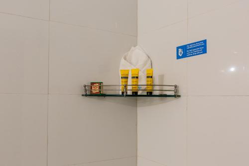 a shelf with yellow boots on a white tiled wall at KSTDC Hotel Mayura Kauvery KRS in Hosa Kannambādi