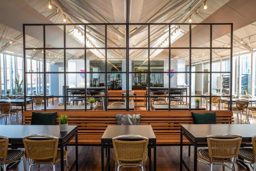 um restaurante com mesas, cadeiras e janelas em Cabinn Aarhus em Arhus