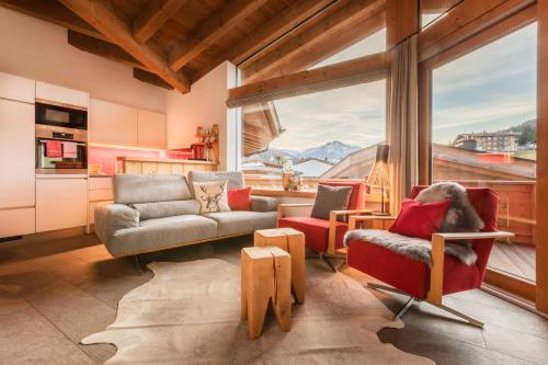 a living room with a couch and chairs and a large window at Löwen Chalets in Seefeld in Tirol