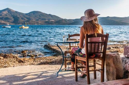 a woman sitting in a chair at a table by the water at Dream Boathouse in Klima