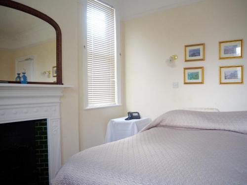 a bedroom with a bed and a mirror and a fireplace at The Old Manse Pickering in Pickering