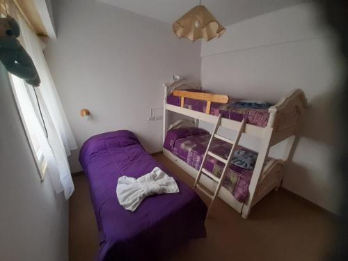 two bunk beds in a small room with purple sheets at Sueños del Golfo in Puerto Madryn