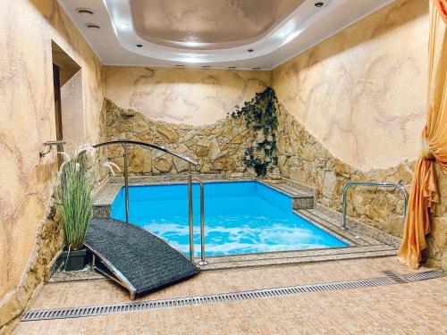 a large swimming pool in a room with a stone wall at Hotel & Spa DENINNA in Vinnytsya