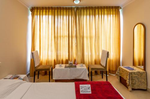 a hotel room with a bed and a table and chairs at KSTDC Hotel Mayura Kauvery KRS in Hosa Kannambādi