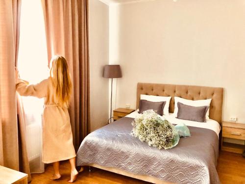 a woman looking out the window of a hotel room at Hotel & Spa DENINNA in Vinnytsya
