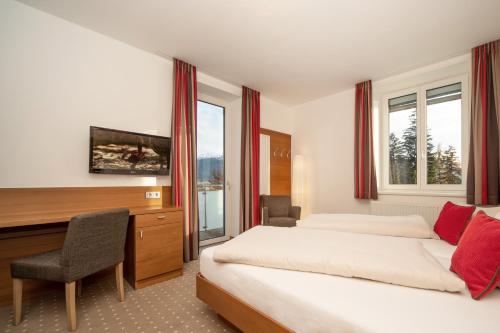 Habitación de hotel con 2 camas, escritorio y TV. en Seehof Innsbruck en Innsbruck