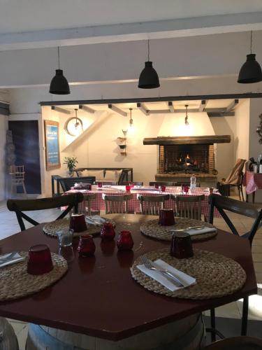 une table en bois avec des assiettes et des serviettes ainsi qu'une cheminée dans l'établissement Mas du Menage en Camargue Manade Clauzel, à Saintes-Maries-de-la-Mer