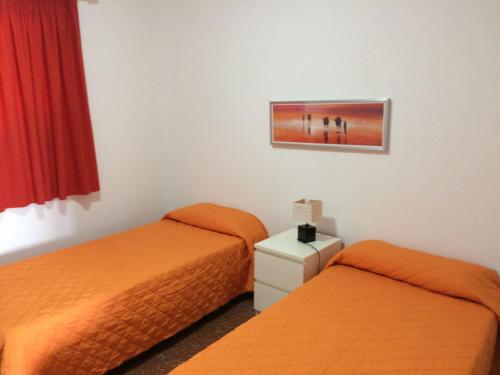 two beds in a hotel room with orange beds at Apartamentos Beatriz in Playa del Ingles