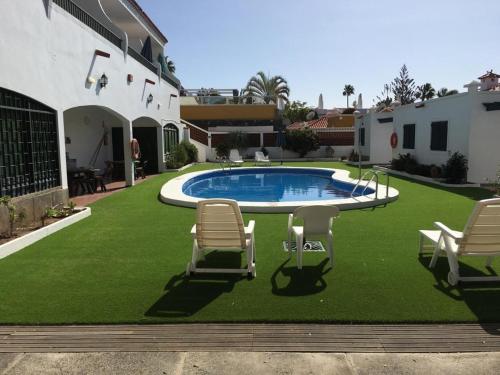 a lawn with chairs and a pool in a yard at Apartamentos Beatriz in Playa del Ingles