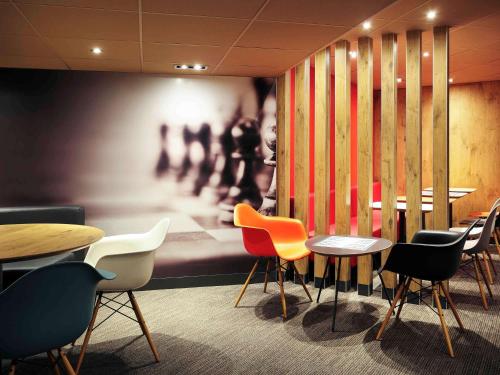 a restaurant with tables and chairs and a painting at ibis Montpellier Centre Comedie in Montpellier