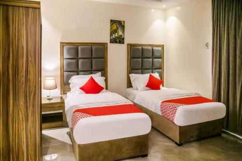 two beds in a hotel room with red pillows at درة ترف 2 للشقق المفروشة المخدمة Durra Taraf Residential 2 in Dammam