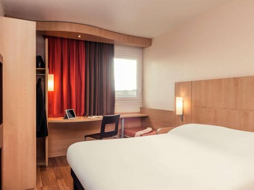 une chambre d'hôtel avec un lit et un bureau dans l'établissement ibis Epinay sur Seine - Gennevilliers, à Épinay-sur-Seine