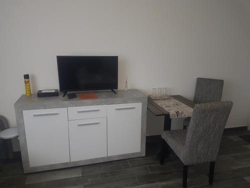 a desk with a tv on top of it with two chairs at Napfény Szállás in Szeged