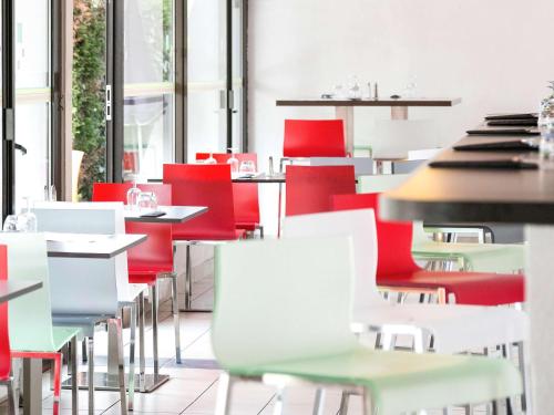 a restaurant with red and white chairs and tables at ibis Styles Bordeaux Aéroport in Mérignac