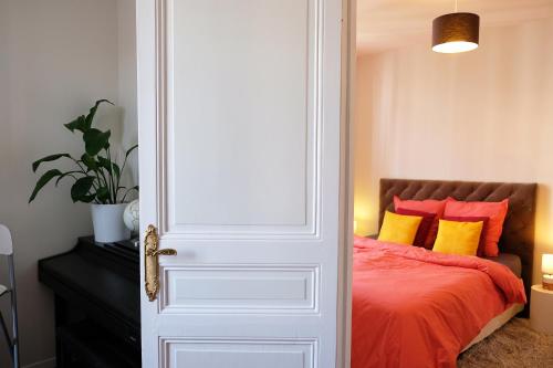 1 dormitorio con 1 cama con almohadas de color naranja y amarillo en Anna's Home Sweet Home en Boulogne-Billancourt