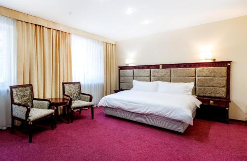 ベルツクにあるMOROZOVO Resort-Hotel&SPAのベッドルーム1室(ベッド1台、椅子2脚、テーブル付)