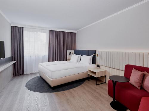ein Schlafzimmer mit einem weißen Bett und einem roten Sofa in der Unterkunft Crowne Plaza Hamburg-City Alster, an IHG Hotel in Hamburg