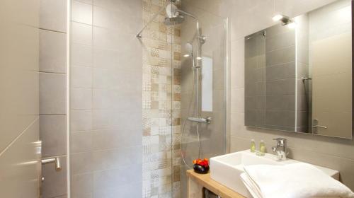 La salle de bains est pourvue d'un lavabo et d'une douche avec un miroir. dans l'établissement Résidence Labellemontagne Rochebrune LES CIMES****, à Orcières