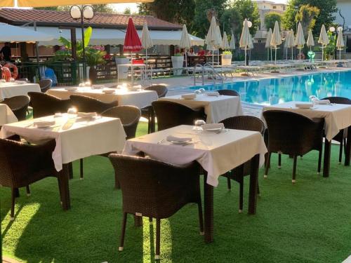 a restaurant with tables and chairs next to a pool at La Pineta Dei Liberti in Lido dei Pini