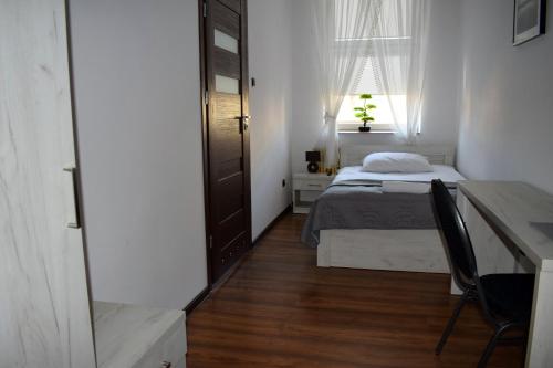 een kleine slaapkamer met een bed en een bureau bij Sepia Restauracja & Noclegi in Jasło