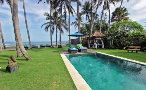 uma piscina com um gazebo e palmeiras em Villa Samudra Luxury Beachfront em Ketewel