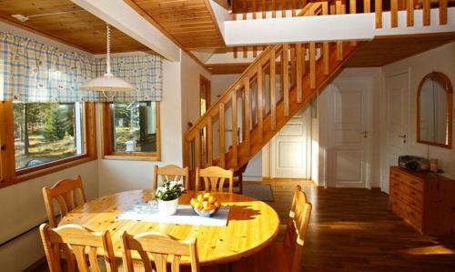 a dining room with a wooden table and a staircase at Marbyfjärden seaside village Loftet in Eckerö