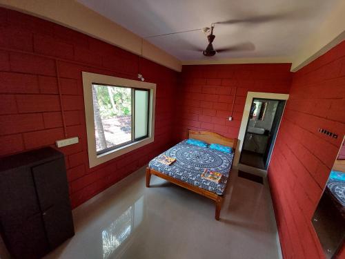 a red room with a bed and a window at Cocopelli Guest House in Gokarna