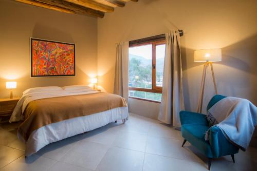 a bedroom with a bed and a chair and a window at Villa del Cielo in Tilcara