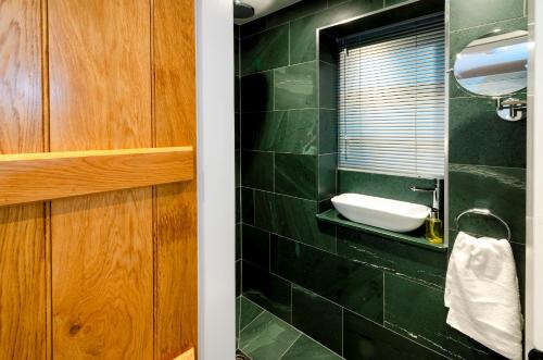 a green tiled bathroom with a sink and a mirror at Juniper Cottage, Chapel Stile, Langdale in Chapel Stile