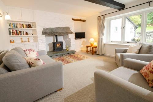 a living room with two couches and a fireplace at Pippins, Elterwater in Chapel Stile