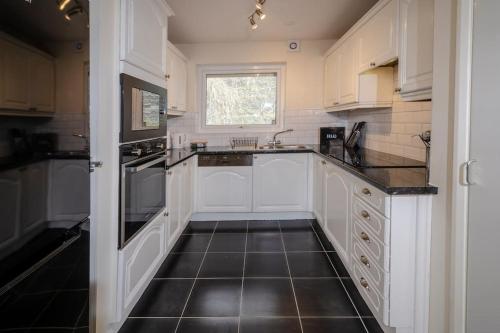 a kitchen with white cabinets and a black tile floor at 27 Thrang Brow, Chapel Stile in Chapel Stile