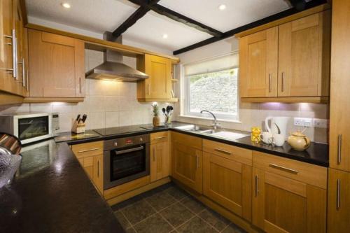 a kitchen with wooden cabinets and a sink and a stove at Christmas Cottage in Chapel Stile