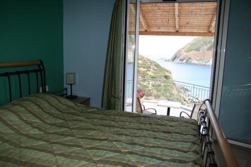 a bedroom with a bed and a view of the ocean at Bel Mare in Agioi Apostoli