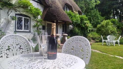 a bottle of wine sitting on a table with glasses at Thatched Eaves in Ibsley