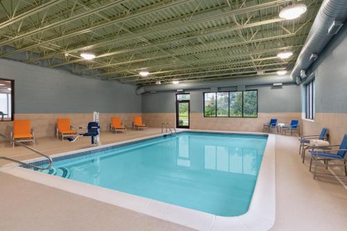 a swimming pool with orange chairs and chairs around it at Holiday Inn Express - Plattsburgh by IHG in Plattsburgh