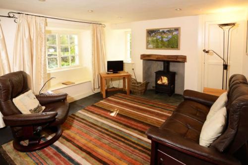 a living room with a couch and a fireplace at Fold Cottage, Outgate near Ambleside in Hawkshead