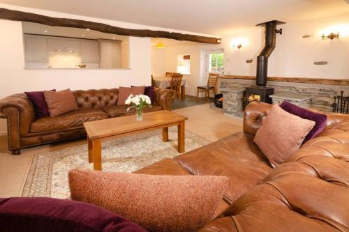 a living room with leather furniture and a fireplace at End Cottage, Chapel Stile in Chapel Stile