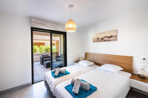 deux lits dans une chambre avec balcon dans l'établissement Résidence Petra d'Oro - Villa Chiappa, à Porto-Vecchio