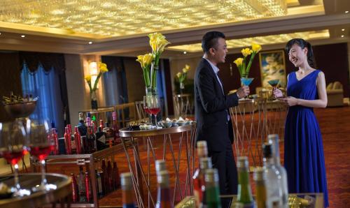 a man and woman standing at a bar with wine glasses at Holiday Inn Foshan Nanhai Central by IHG in Foshan