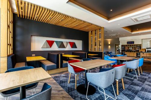 a restaurant with wooden tables and blue chairs at Holiday Inn Express - Bicester by IHG in Bicester