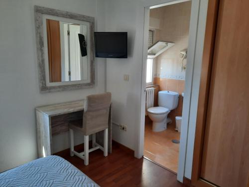 a bathroom with a toilet and a desk with a mirror at Hotel a Muradana in Muros