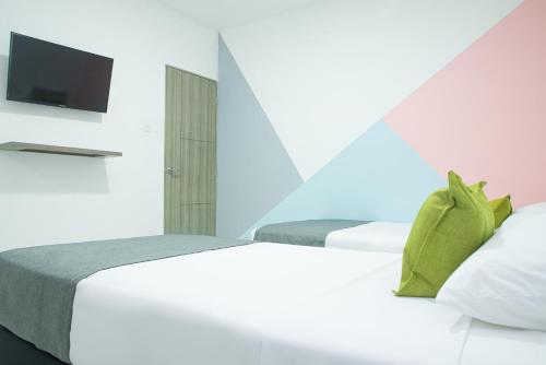 a bedroom with two beds and a flat screen tv at Hotel Ayenda House Concepción 1317 in Barranquilla