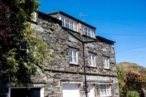 an old stone building with white windows on it at Rosegate House, Elterwater in Elterwater