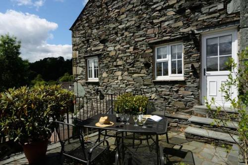 a table and chairs outside of a stone house at Rosegate House, Elterwater in Elterwater