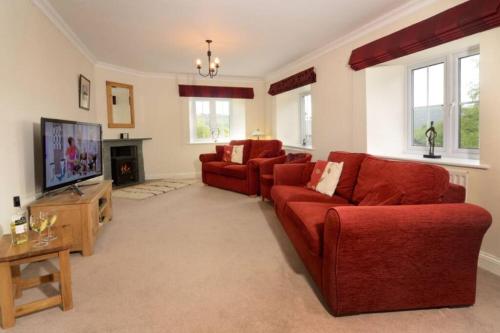 a living room with two red couches and a tv at Rosegate House, Elterwater in Elterwater