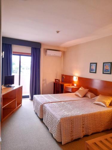 una camera d'albergo con letto e TV di Hotel das Taipas a Guimarães