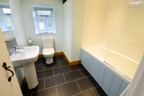 a bathroom with a sink and a toilet and a tub at Stickle Cottage, Great Langdale in Grasmere