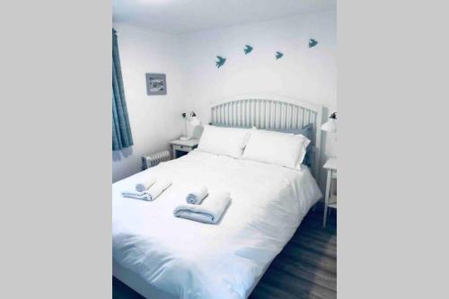 1 dormitorio con 1 cama blanca y 2 toallas en Fuchsia Apartment Tranquil Modern Seaside Apartment on the Wild Atlantic Way, en Galway