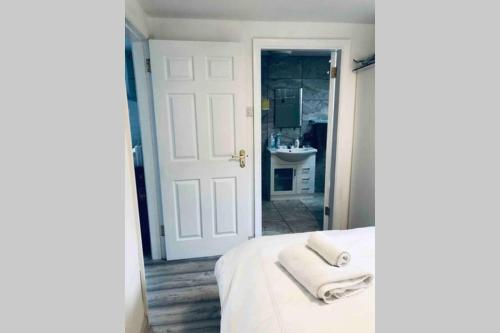 a white bedroom with a bed with towels on it at Fuchsia Apartment Tranquil Modern Seaside Apartment on the Wild Atlantic Way in Galway