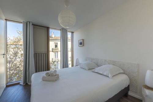 - une chambre dotée d'un lit blanc avec un animal rembourré dans l'établissement Duplex En Aparté - Première conciergerie, à Montpellier